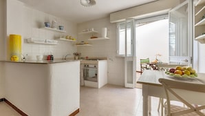 Une cuisine avec des meubles blancs, un îlot central et un coin repas comprenant une table et des chaises.