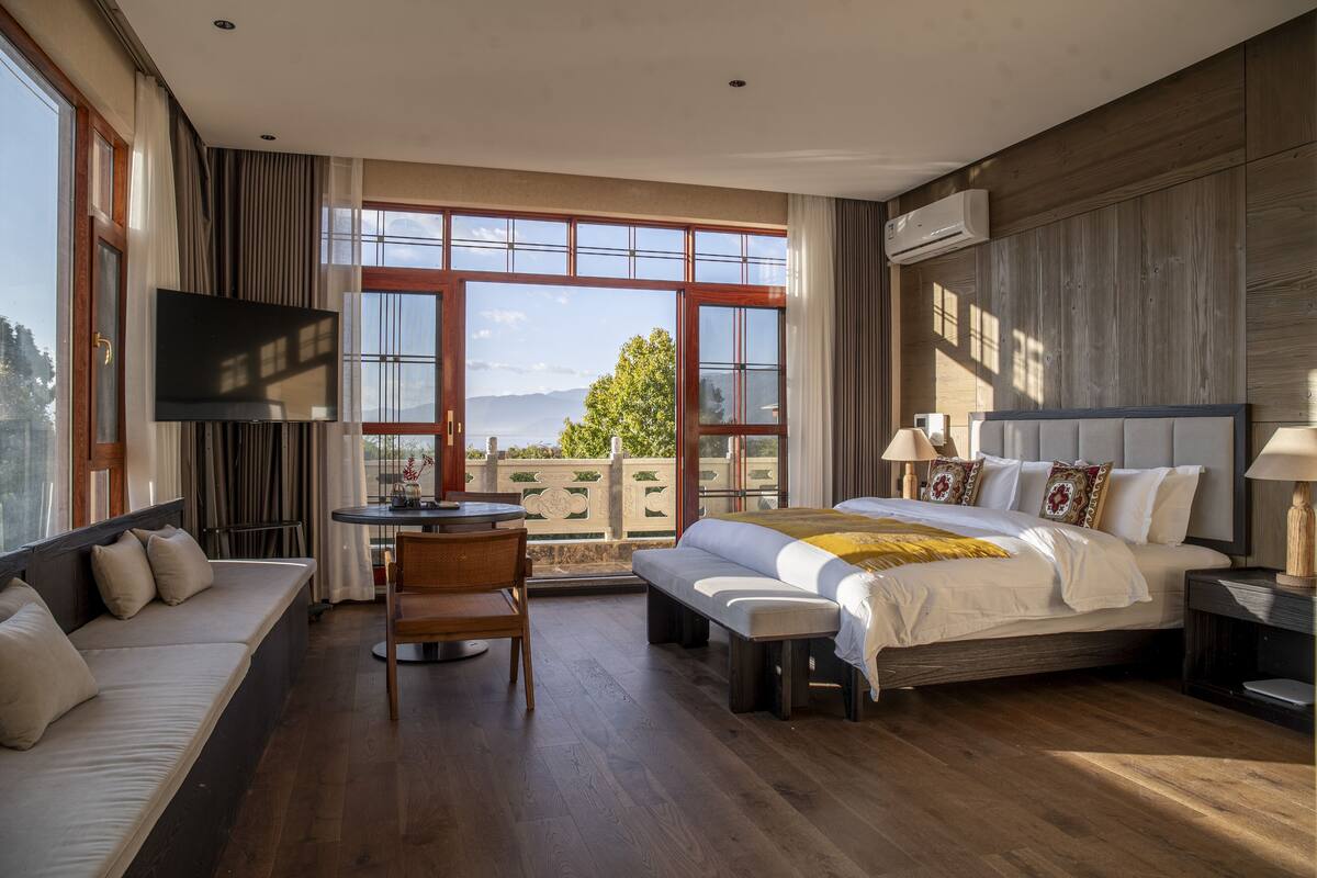 Une chambre avec un grand lit, un canapé, un bureau et une télévision.