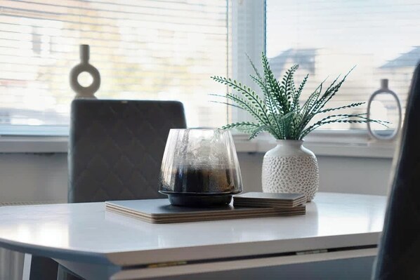 A table with a glass container, a potted plant, and a stack of books.