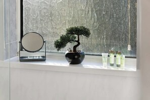 A potted bonsai tree, a round mirror, and three bottles on a windowsill. - Darlington Central 4BR with Parking and Free WiFi (Darlington)