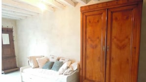 A room with a white sofa, a wooden wardrobe, and a tiled floor.