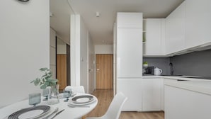 A modern kitchen with white cabinets, a dining table set with plates, glasses, and cutlery.