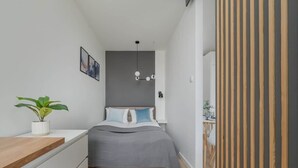 A modern bedroom with a bed, bedside table, and a potted plant.