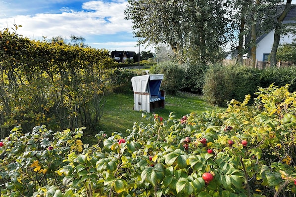 A garden with a variety of plants and a white chair with a blue cover.