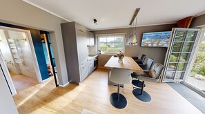 A modern kitchen with a dining area, large windows, and a view of the outdoors.