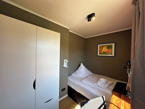 A bedroom with a bed, a wardrobe, a painting, and a lamp.