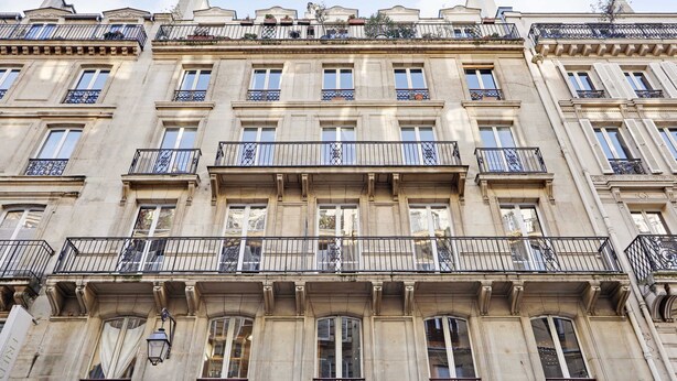Un edificio de varios pisos con balcones, ventanas amplias y detalles arquitectónicos clásicos.