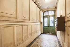 Un pasillo con paneles decorativos y baldosas de diseño que conducen a una puerta verde con paneles de vidrio.