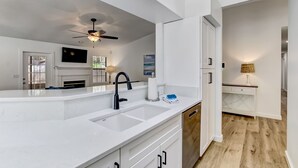 A modern kitchen with a white countertop, black faucet, and a ceiling fan.