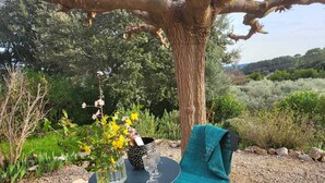 Ein Tisch im Freien mit Blumen in einer Vase, einem gestreiften Behälter und einem türkisfarbenen Tuch.