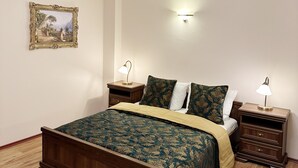 Een slaapkamer met een houten bed, twee nachtkastjes met lampen, een kroonluchter, een wandlamp en een lijst met een afbeelding aan de muur.