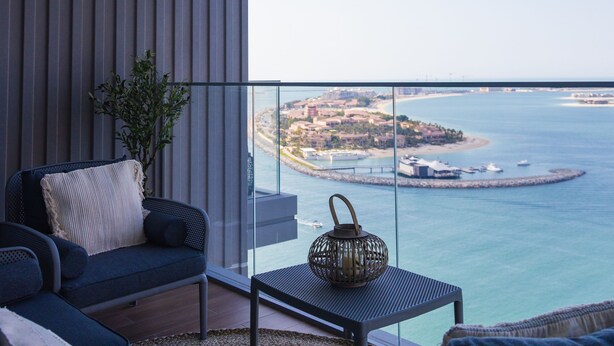A balcony with a sofa, a small table, and a potted plant. - 3BD Haven with Sweeping Water Views (Dubai)