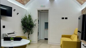 Un interior moderno con techo de ladrillo, zona de comedor con sillas amarillas, sofá amarillo y área de cocina con refrigerador.