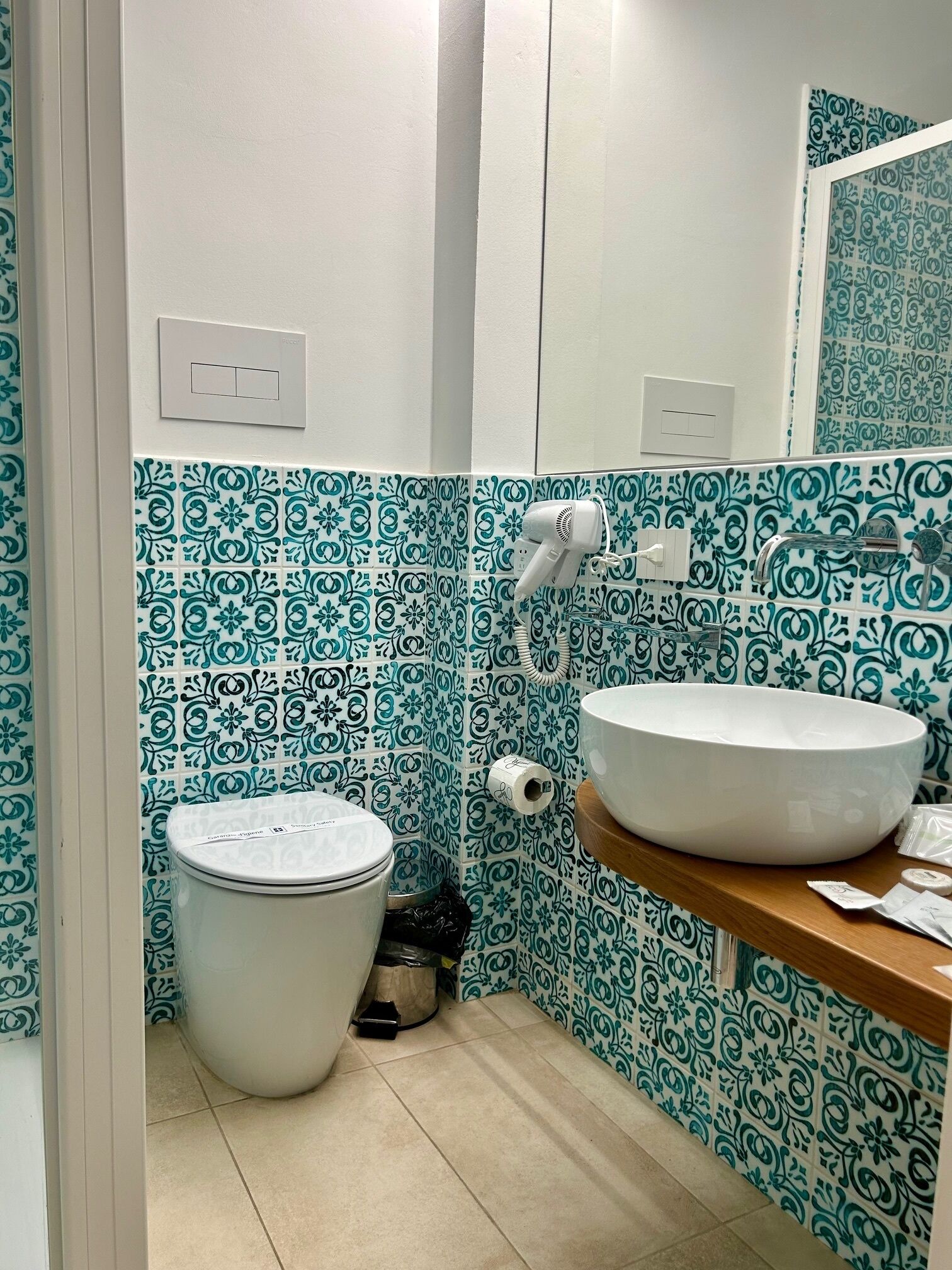 A bathroom with a toilet, a sink, and a hairdryer on the wall.