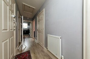 Classic doors lead to a kitchen with dark cabinets and a window.