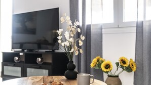 A round wooden table with a plate of croissants, a mug, and a vase with white flowers and sunflowers. - Bella Casa Pitsidia (Faistos)