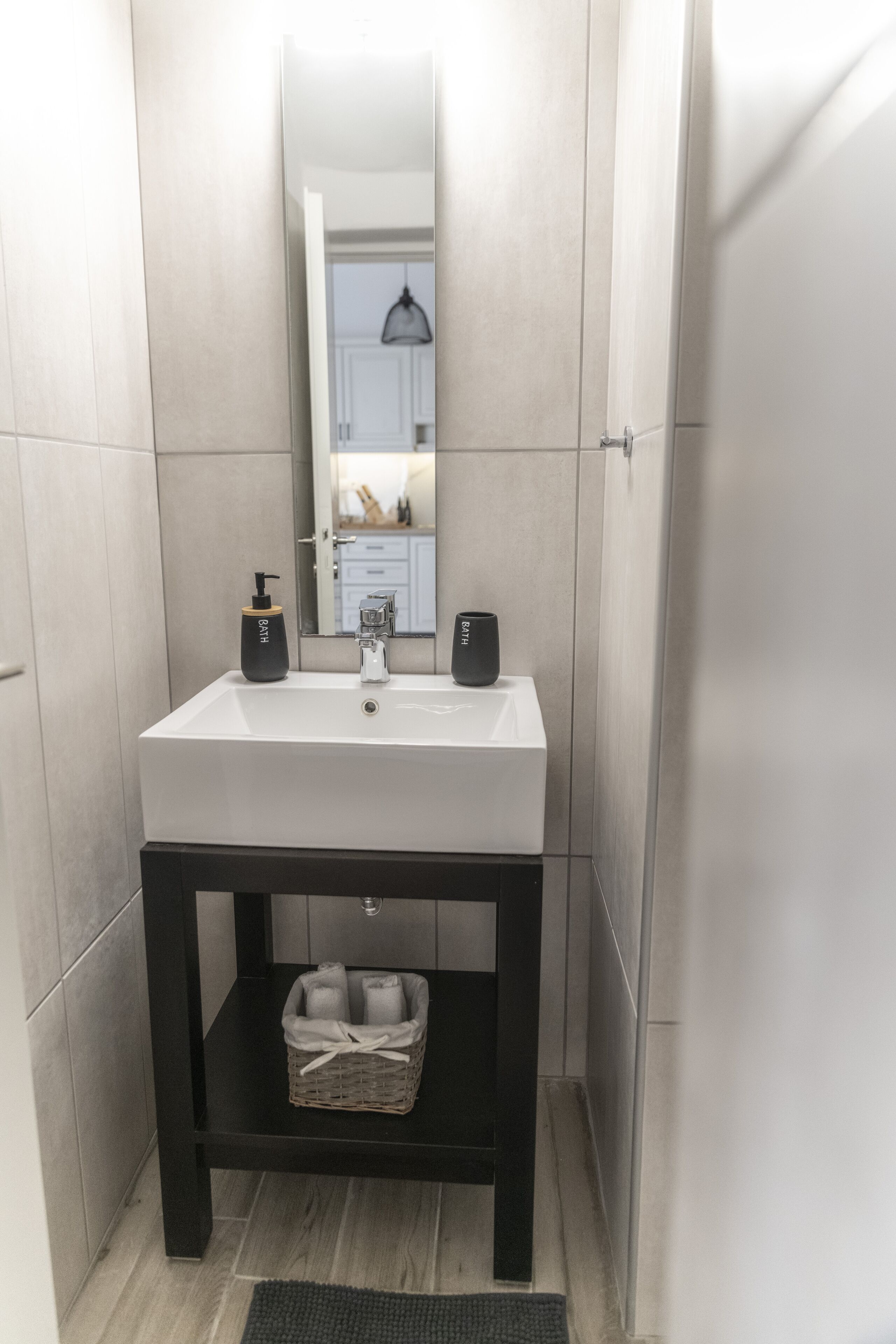 A modern bathroom with a white sink, black soap dispenser, and a mirror above it.