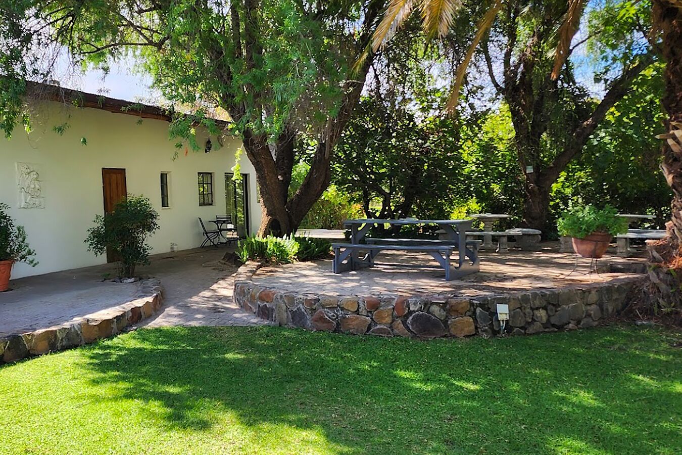 A courtyard with stone benches, a picnic table, and potted plants.