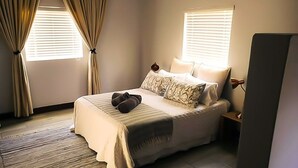 Een slaapkamer met een bed, gordijnen, een nachtkastje en een bedtafel.