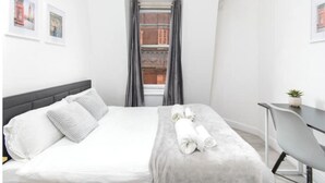 Une chambre d’hôtel avec un lit, un bureau et une fenêtre avec des rideaux.