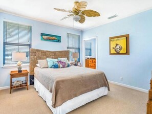 Cozy retreat with a large bed, ceiling fan, and artwork adorns the walls.