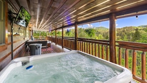 A hot tub on a wooden deck with a view of a forested landscape. - Tequila Moon: Dive Into Paradise (Sevierville)