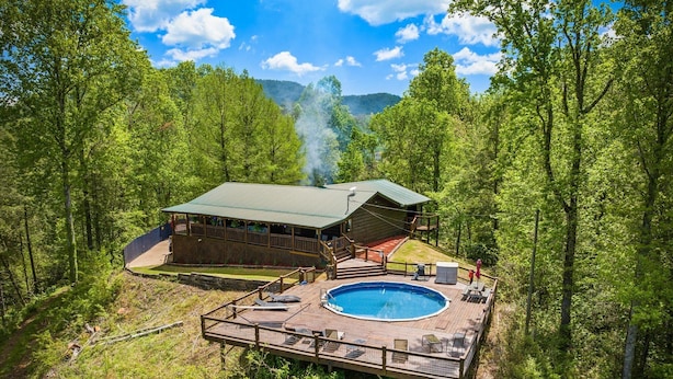 A cabin with a deck and an outdoor pool surrounded by forest. - Tequila Moon: Dive Into Paradise (Sevierville)