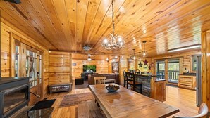A cozy log cabin interior with a wooden dining table, benches, a fireplace, and a kitchen area. - Tequila Moon: Dive Into Paradise (Sevierville)