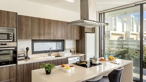 A modern kitchen with wooden cabinets, a large island with a sink, and a view of the outside. - stunning and luxurious villa is located in the popular resort area of Protaras (Protaras)