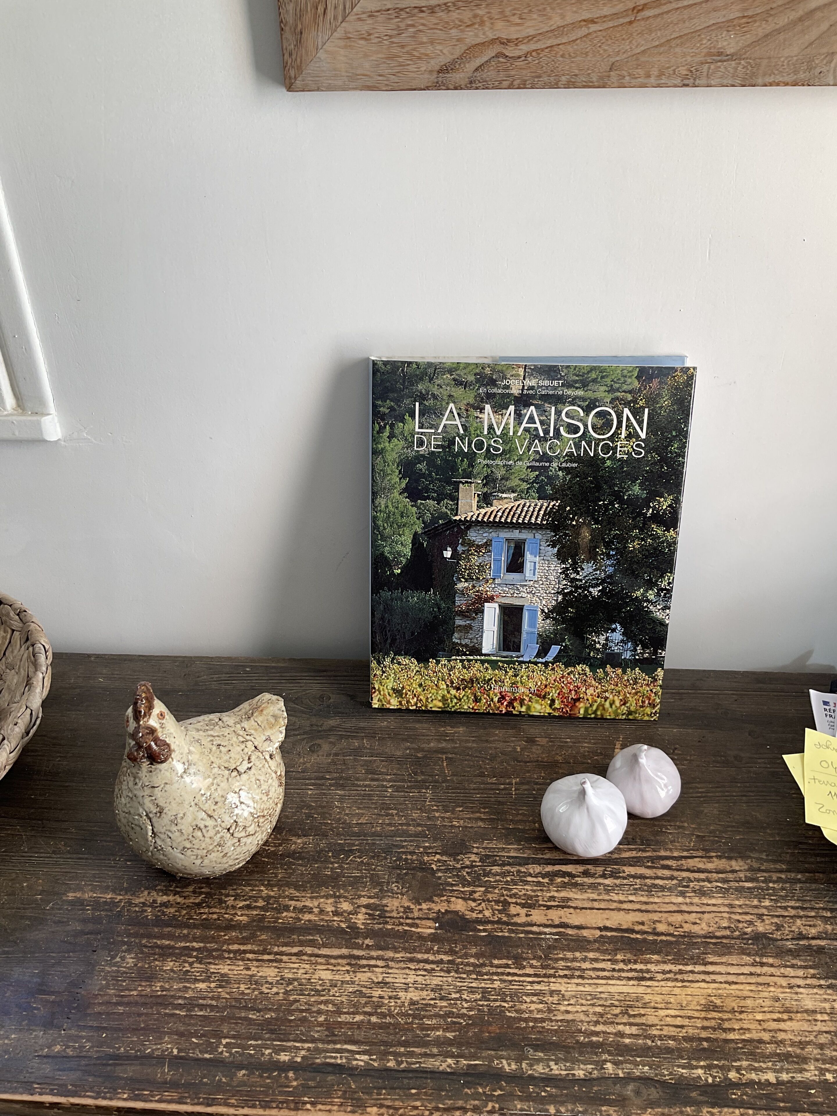 A book titled 'LA MAISON DE NOS VACES' on a wooden surface with decorative items.
