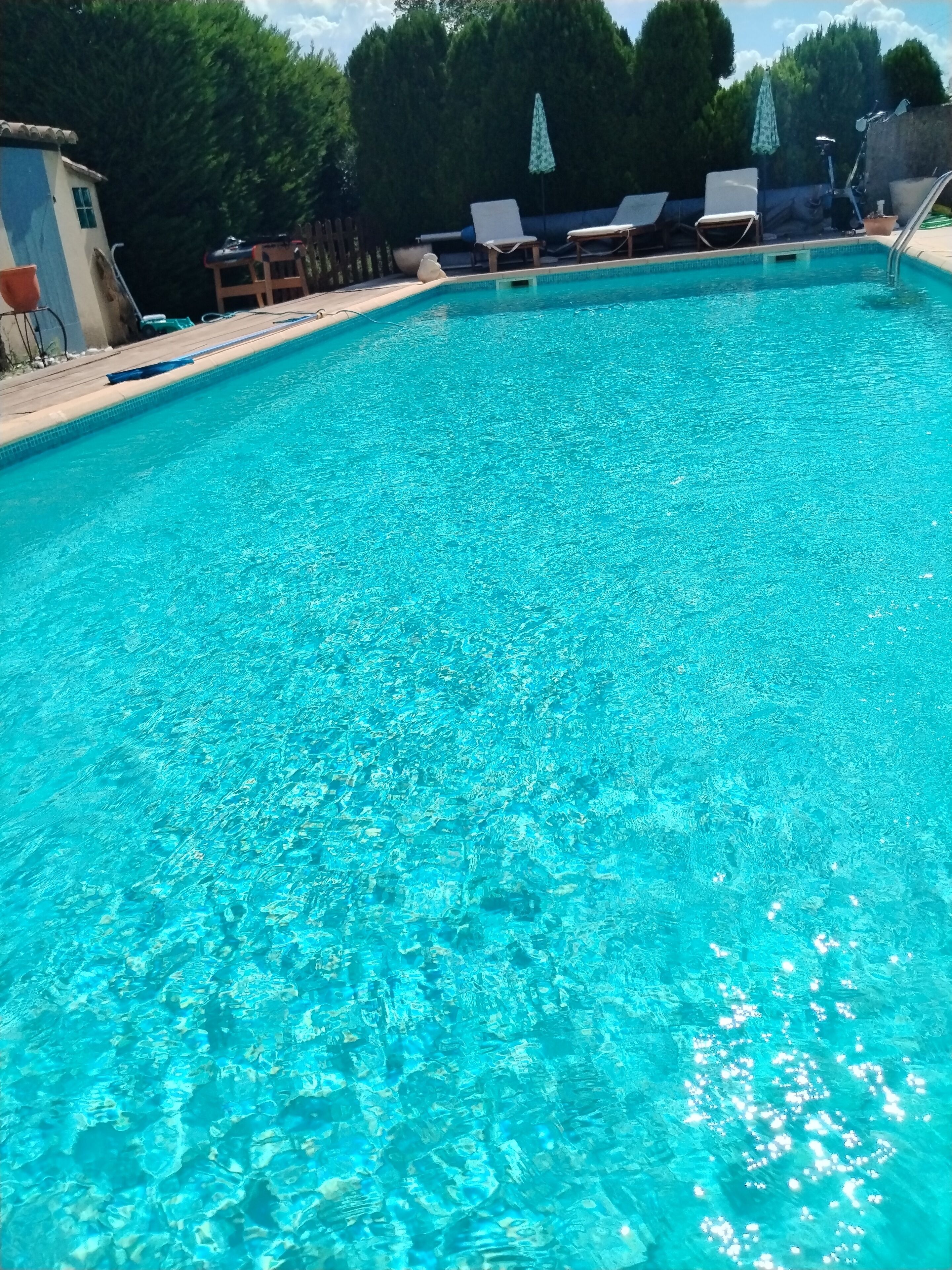 A clear blue pool with lounge chairs and umbrellas.