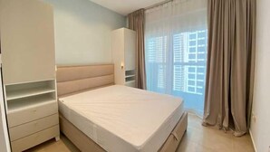 Ein Schlafzimmer mit Bett, Kleiderschrank und einem Fenster mit Vorhängen.