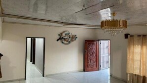 A spacious room with a high ceiling, a chandelier, a decorative wall piece, and a wooden door. - ELITE VILLA HOMES LIMITED

HOME AWAY HOME 
 (LUSAKA)