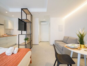 A modern hotel room with a bed, a sofa, a dining table, and a kitchenette. - Shabolo Apartments las Palmas (Las Palmas de Gran Canaria)