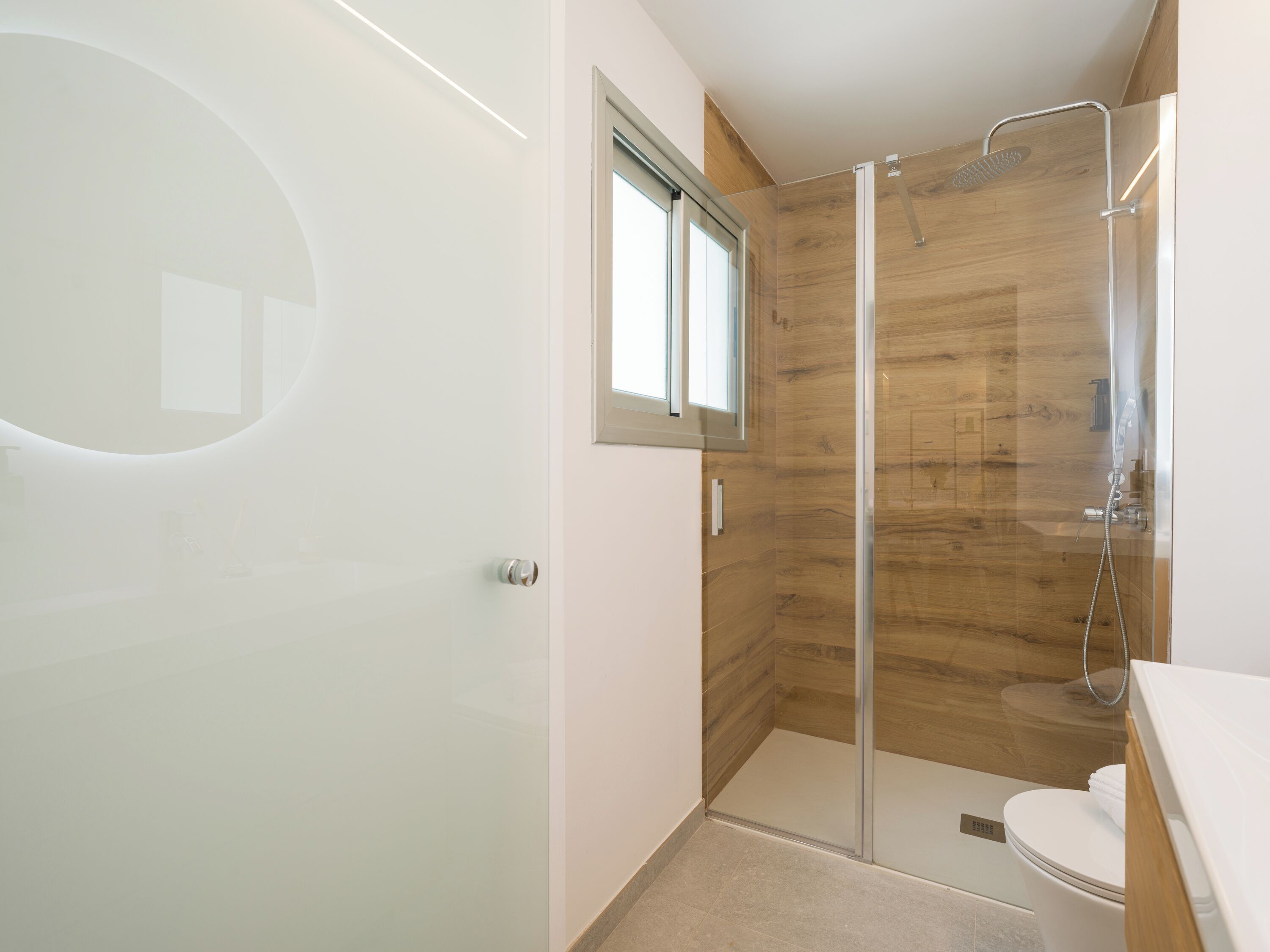 A modern bathroom with a glass shower enclosure, a toilet, and a sink.