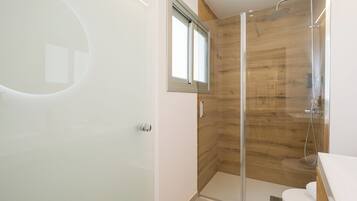 A modern bathroom with a glass shower enclosure, a toilet, and a sink.