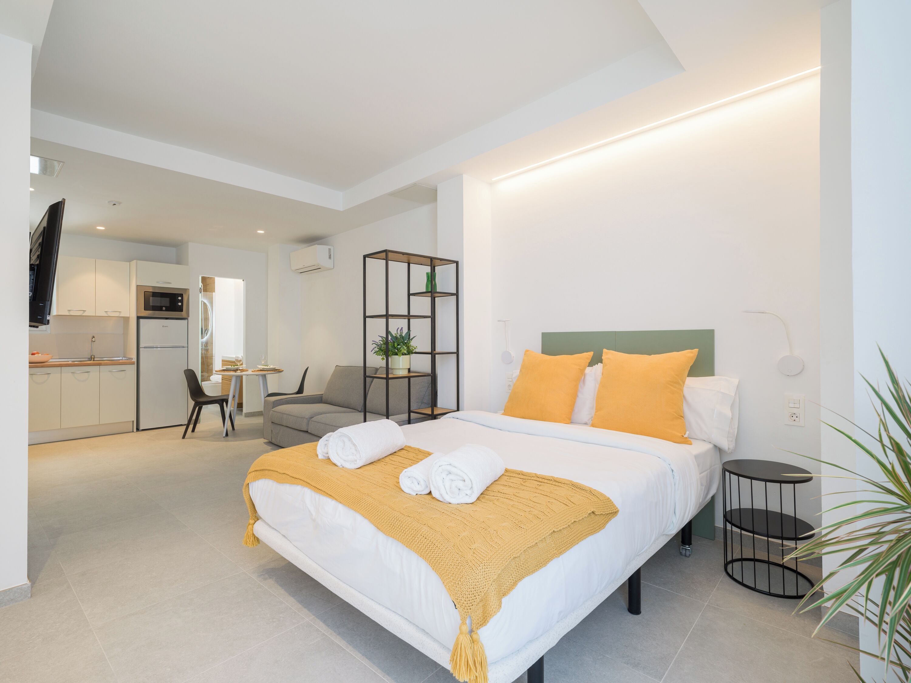 A modern hotel room with a bed, bedside table, and a small desk area.