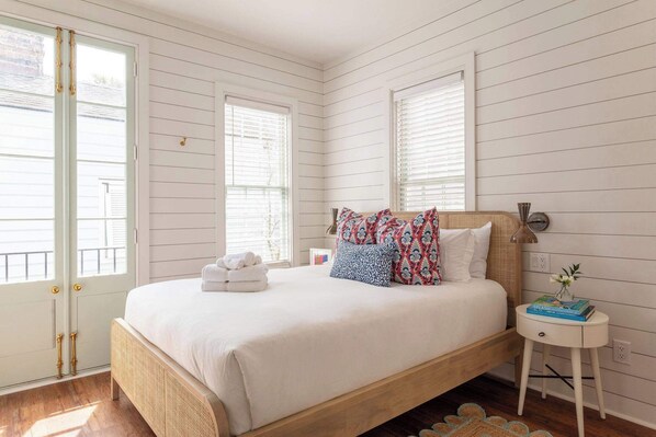 A bedroom with a wooden bed, white walls, and a small bedside table with a book and a vase.