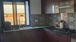 A kitchen with dark wooden cabinets, a gas stove, and a window with a view of a building outside.