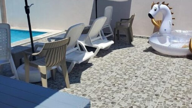 A poolside area with lounge chairs, umbrellas, and a swan-shaped inflatable float.
