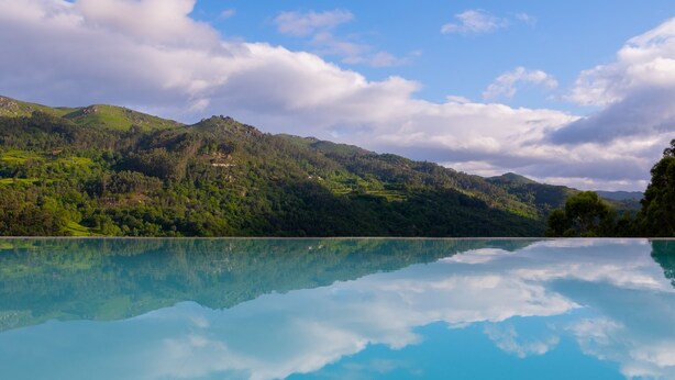 Ein klarer See mit Spiegelung des Himmels und der umliegenden Hügel.