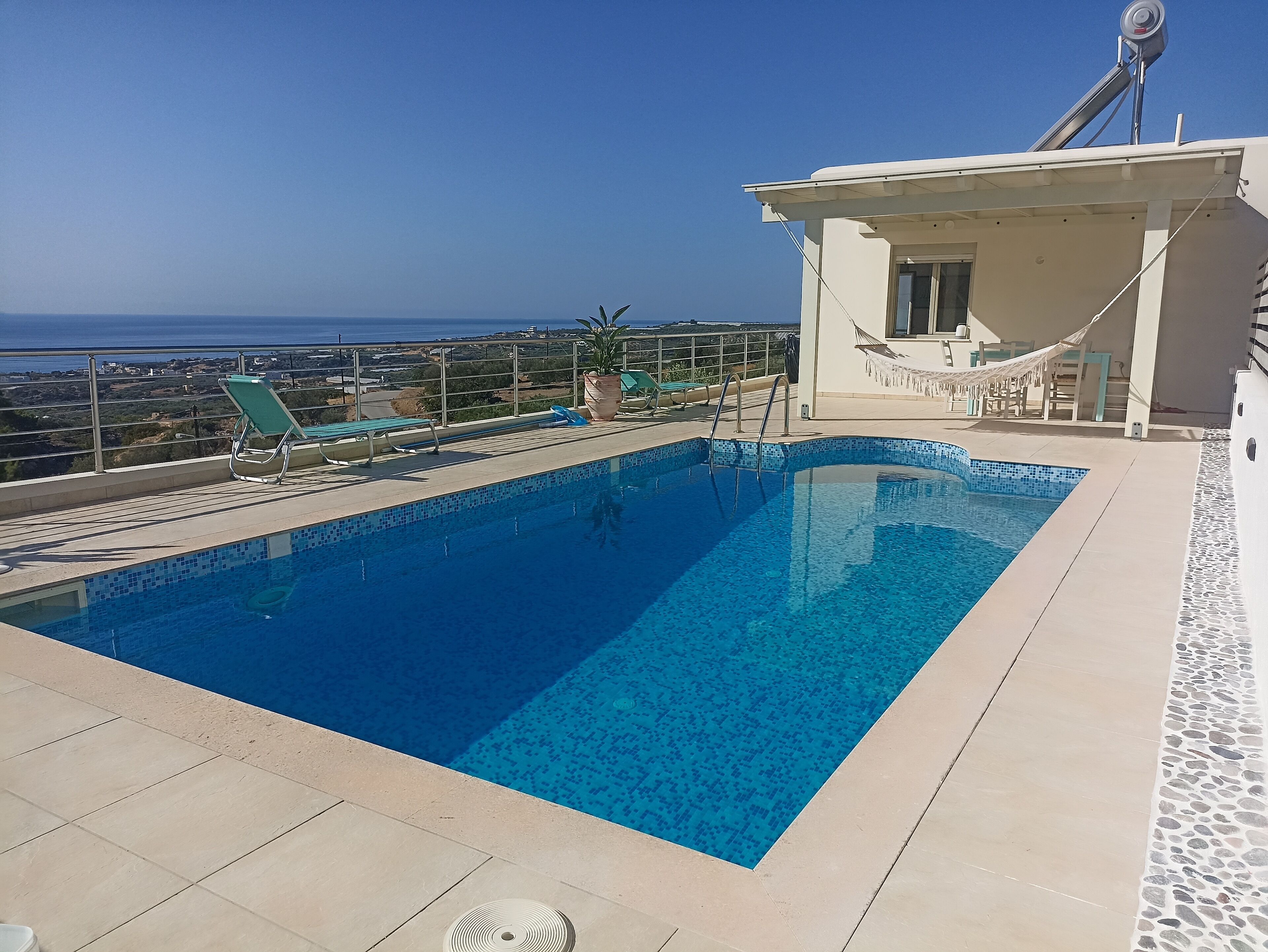 Ein rechteckiger Pool mit blauen Fliesen, umgeben von beigen Fliesen und einer weißen Wand mit einem Fenster.