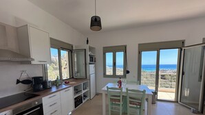 A modern kitchen with a view of the ocean, a dining area with a table and chairs, and a large oven.