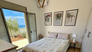 A bedroom with a bed, a desk, and a view of the outdoors.