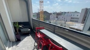 A balcony with grey tiled flooring, a potted plant, and red chairs. - Appartement F4 Proche du Stade de France (Saint-Denis)