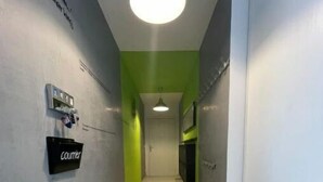 A hallway with a green accent wall, a sign reading "Couriers," and a ceiling light. - Appartement F4 Proche du Stade de France (Saint-Denis)