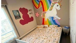 A bedroom with a bed, a ceiling light, a wall mural of a unicorn, and a small Eiffel Tower model. - Appartement F4 Proche du Stade de France (Saint-Denis)