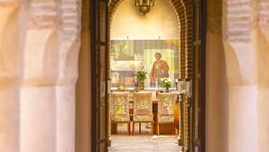 An arched corridor with a tiled floor, leading to a room with a table and chairs.