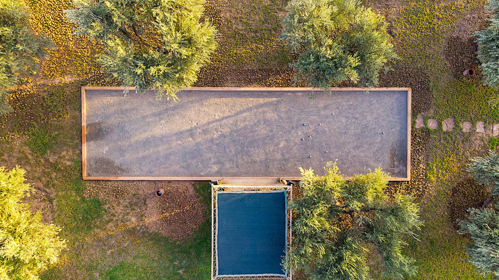 Luchtbeeld van een rechthoekig gebouw met een plat dak, omgeven door dichte begroeiing.