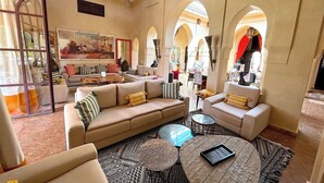 A spacious living area with a beige sofa set, a coffee table, and patterned rugs.